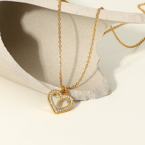 The Devotion open heart necklace on a white silk background, with dramatic shadows that highlight the sparkle of the pavé crystals.