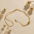 Extreme close-up of the dotted bead texture on the minimalist gold chain.