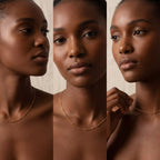Model with dark skin wearing minimalist gold beaded chain necklace layering piece.