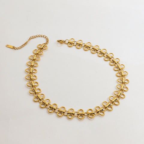 A detailed studio shot of The Elodie Choker by Luminova, laid out in a circle to showcase its delicate, continuous chain of minimalist gold clover links.