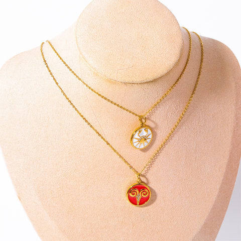 Layered gold zodiac coin necklaces red and white enamel on jewelry display bust.