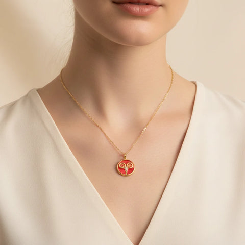Red enamel gold coin necklace styled on woman with v-neck white shirt.