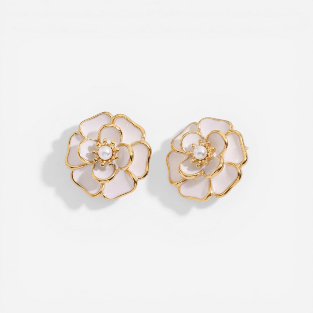 A detailed studio shot of The Fleur Studs by Luminova, showcasing the iconic white enamel camellia flower design with a central pearl and gold trim.