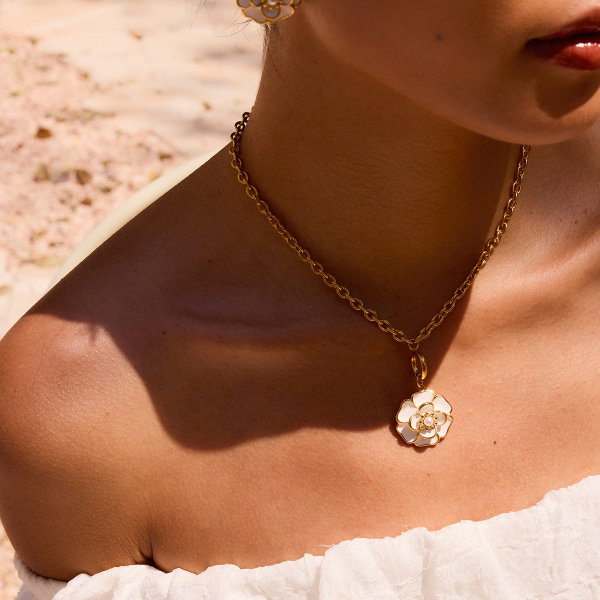 Close-up of a model on the beach, with The Fleur Pendant as the perfect centerpiece for a chic, sophisticated vacation look.