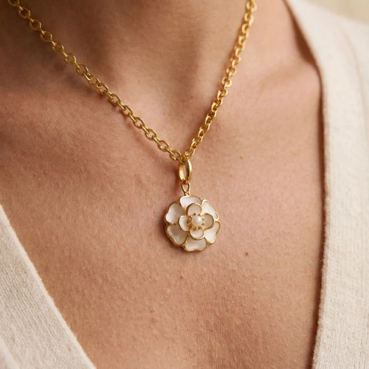 A beautiful close-up of The Fleur Pendant on a model's collarbone, highlighting the intricate details of the white camellia and its central pearl.