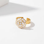 White enamel flower ring with gold rim and crystal center adjustable band.