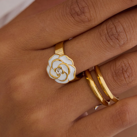 A beautiful close-up of The Fleur Ring on a model's hand, highlighting the vibrant white enamel and the comfortable fit of the open, adjustable band.