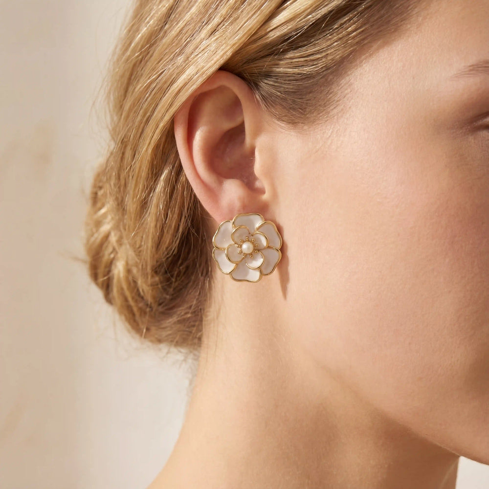 A beautiful close-up of a model in a garden setting, wearing The Fleur Studs which add a touch of timeless elegance to her look.