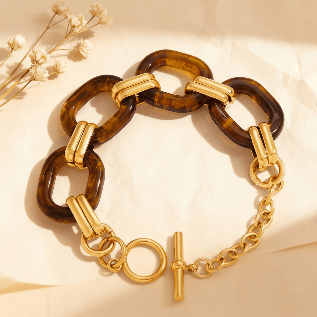 The Florence Link Bracelet by Luminova displayed on a luxurious silk background, showing a detailed view of the warm tortoiseshell resin links and the 18k gold-plated toggle clasp.