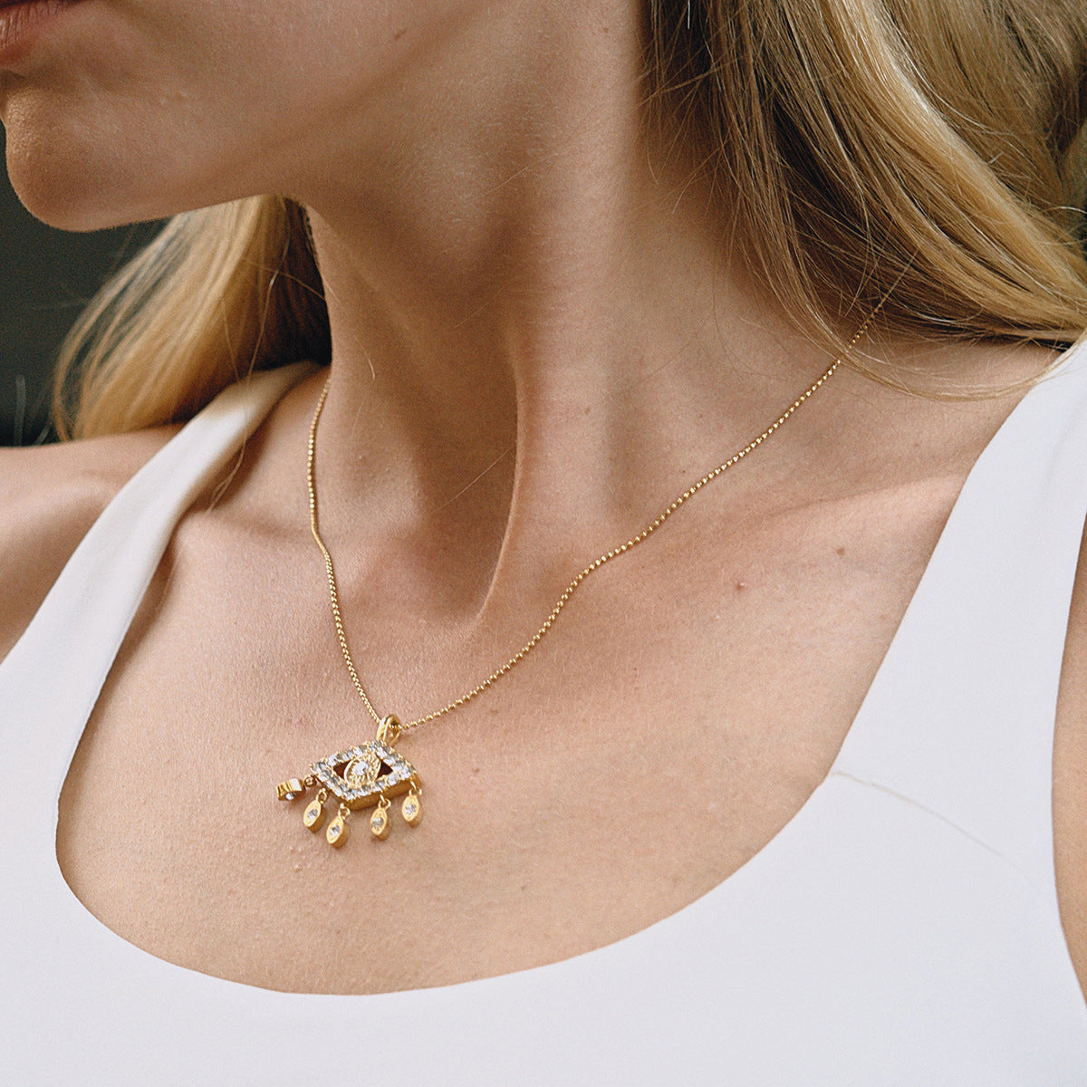A beautiful close-up of a model wearing The Fortuna Necklace, highlighting its delicate placement on the collarbone and the brilliant sparkle of the evil eye pendant.