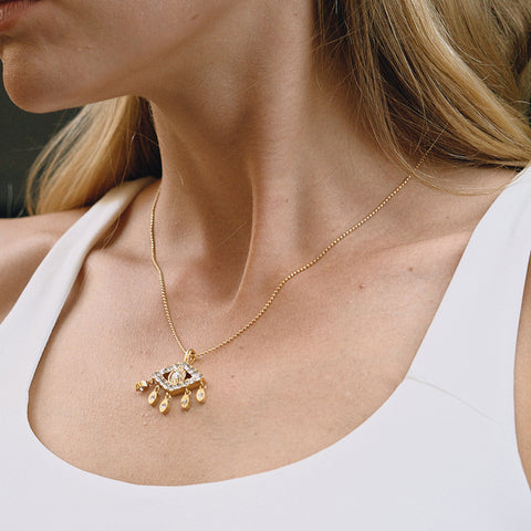 A beautiful close-up of a model wearing The Fortuna Necklace, highlighting its delicate placement on the collarbone and the brilliant sparkle of the evil eye pendant.