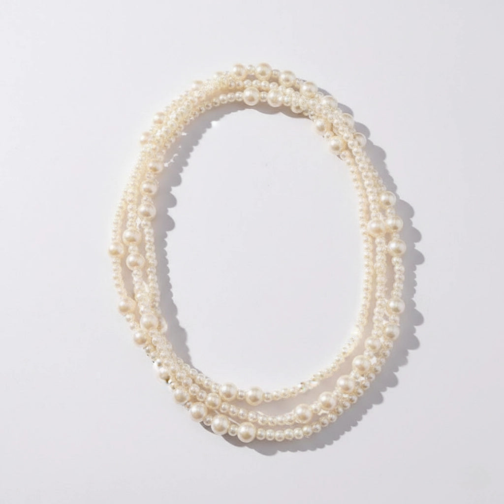 A detailed studio shot of The Gabrielle Necklace by Luminova, an extra-long pearl rope coiled to showcase its lustrous, multi-sized pearls.