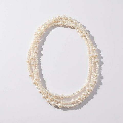 A detailed studio shot of The Gabrielle Necklace by Luminova, an extra-long pearl rope coiled to showcase its lustrous, multi-sized pearls.