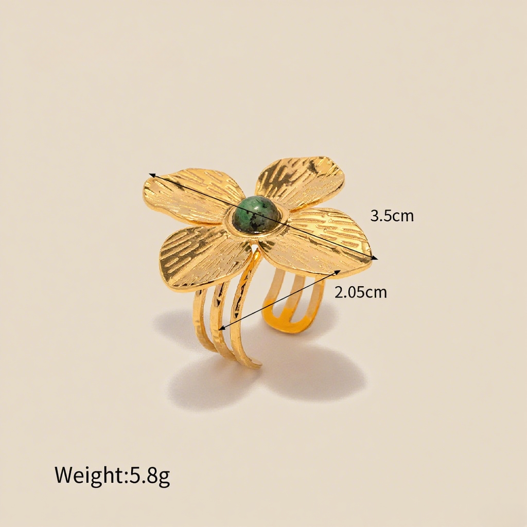 A macro shot of the Gaia Ring on a model's finger, focusing on the way light plays across the hammered texture of the gold petals and the deep, natural color of the central green stone