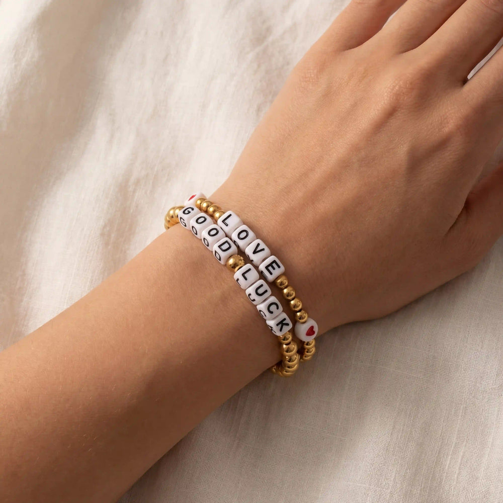 Lifestyle photography of woman styling stacked word bracelets friendship jewelry trend.