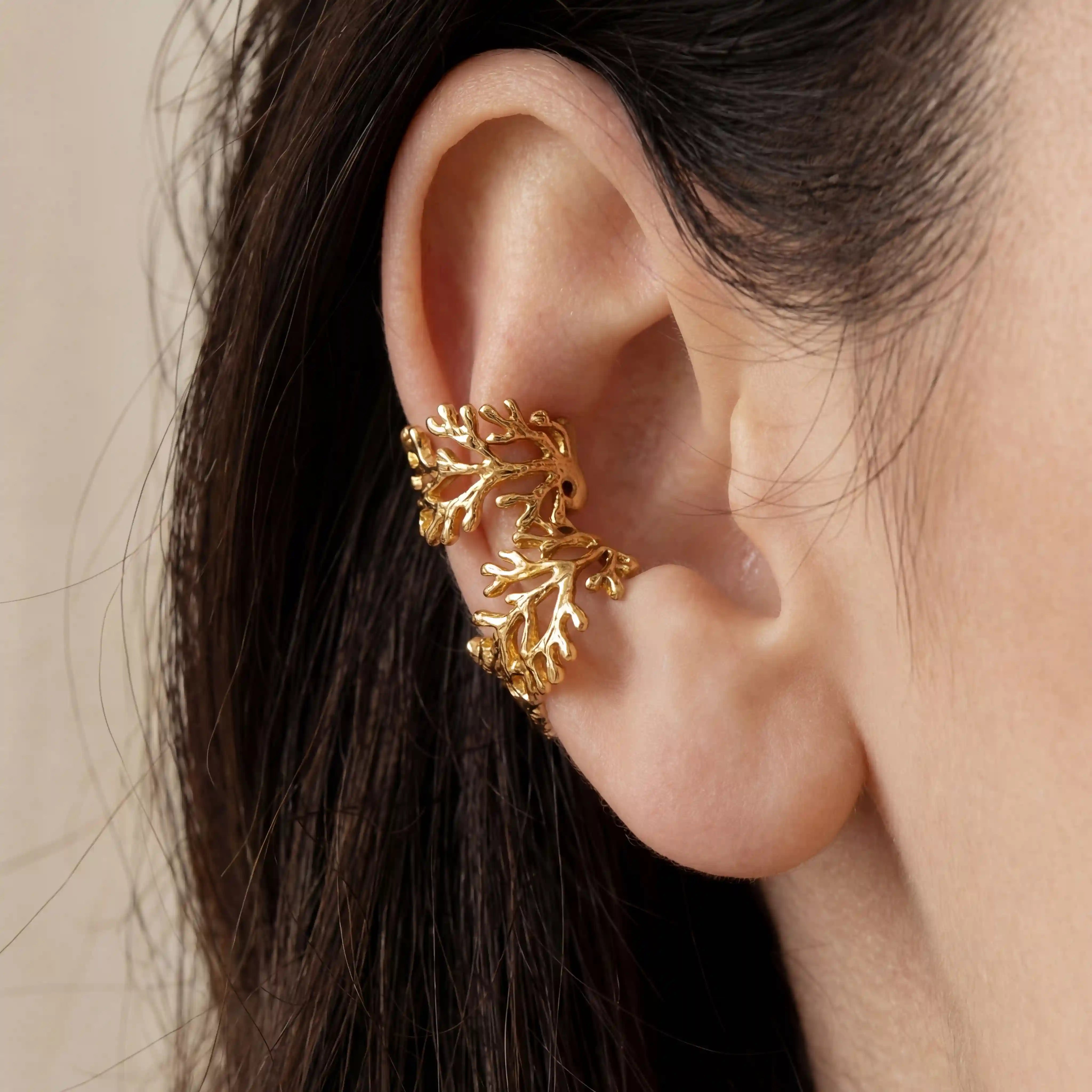 Close up of gold coral branch ear cuffs on model ear no piercing cartilage jewelry.
