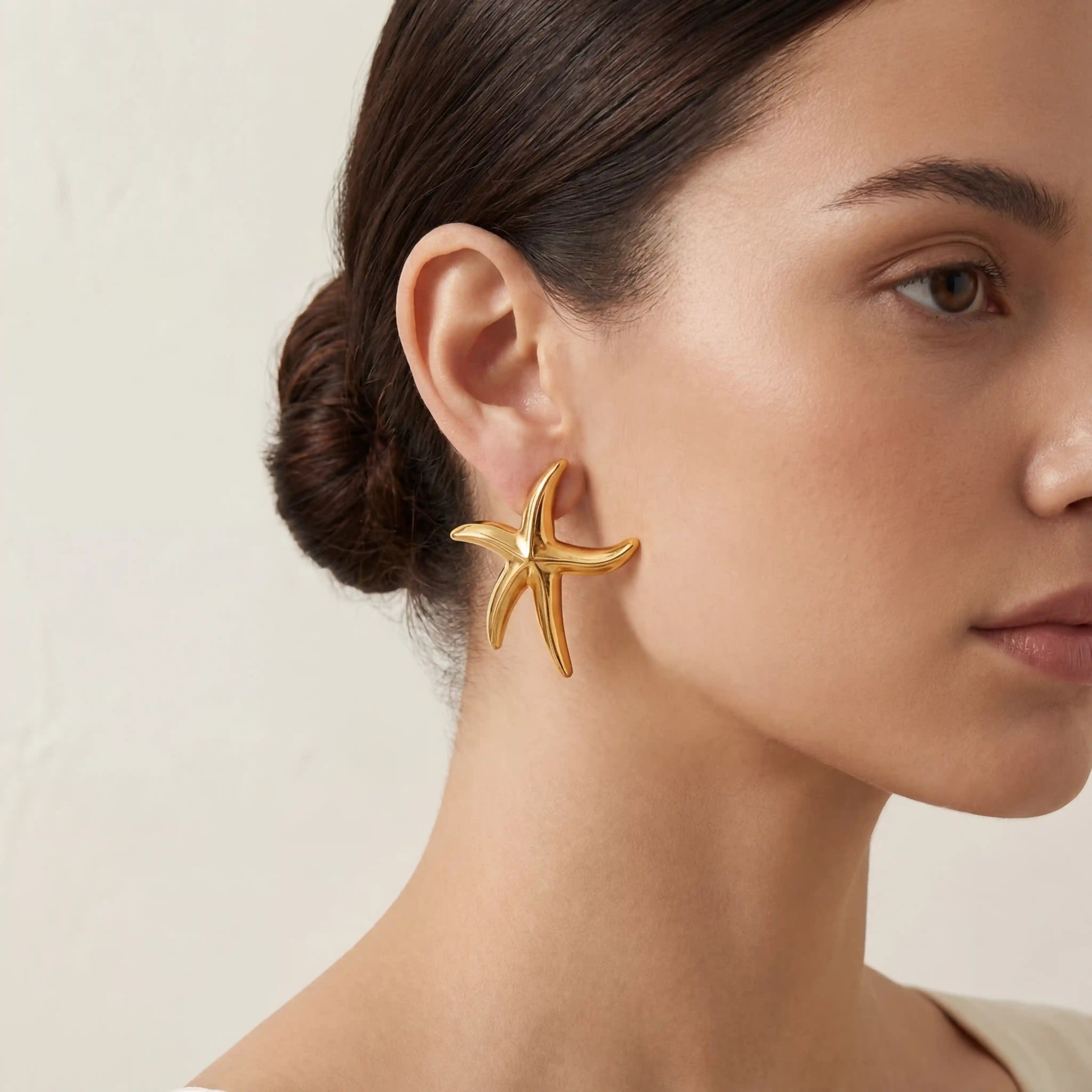 Close up of woman wearing chunky gold starfish statement earring mermaidcore style. Main image