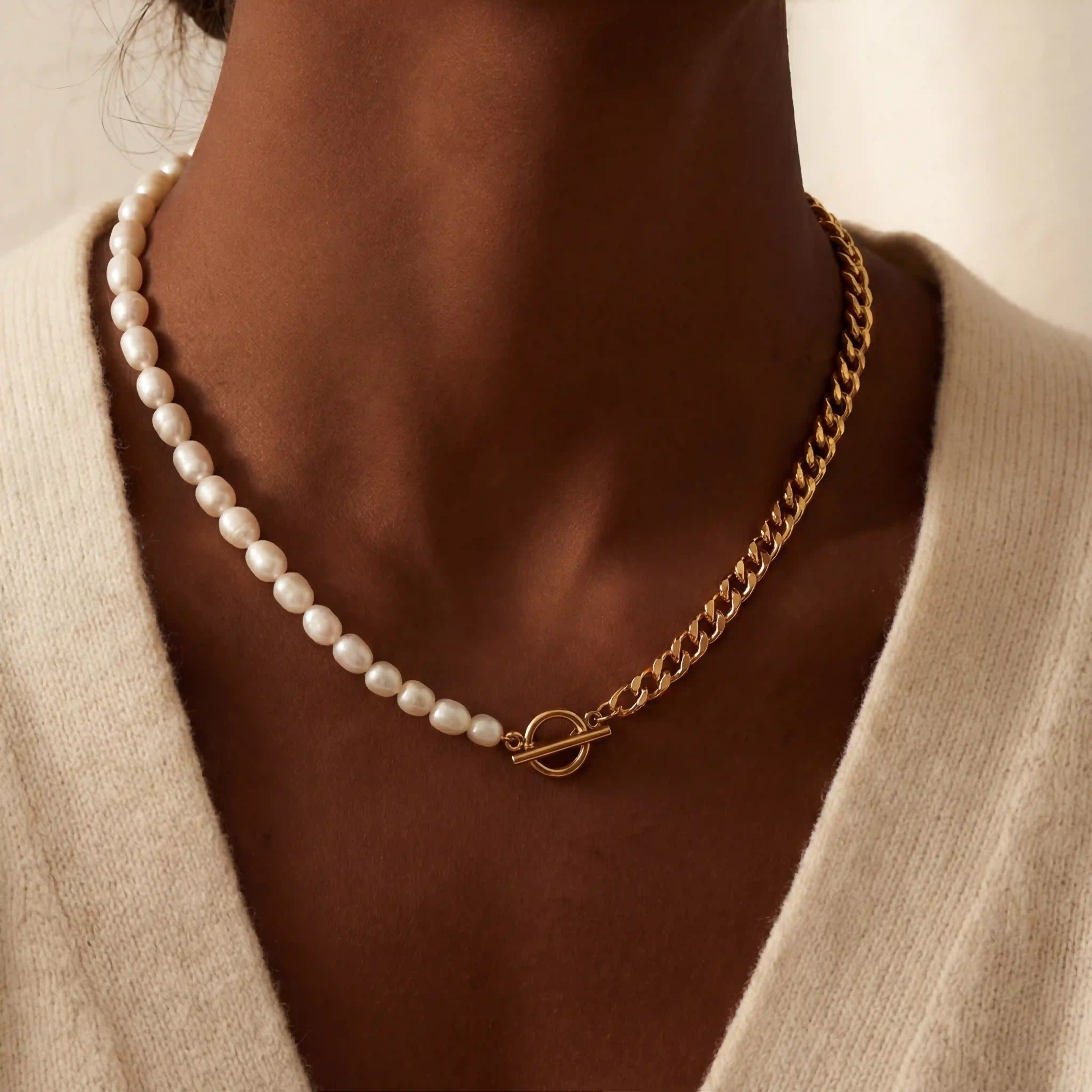 Close up of woman with dark skin wearing half pearl half gold chain necklace with toggle clasp.