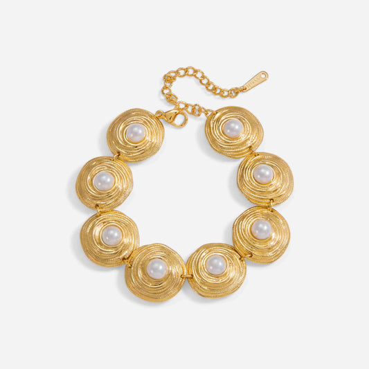 A detailed studio shot of The Hera Bracelet by Luminova, showcasing its vintage design with a series of textured gold medallions, each centered with a lustrous white pearl.