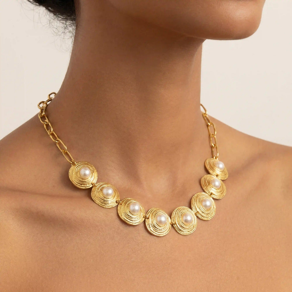 A beautiful model wearing The Hera Necklace with an off-the-shoulder top, highlighting its majestic presence and how it sits elegantly on the collarbone.