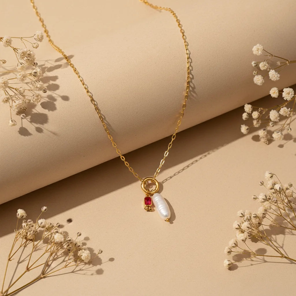 A full view of the personalized Astoria Necklace with the vibrant July birthstone (ruby red), styled with delicate dried flowers.