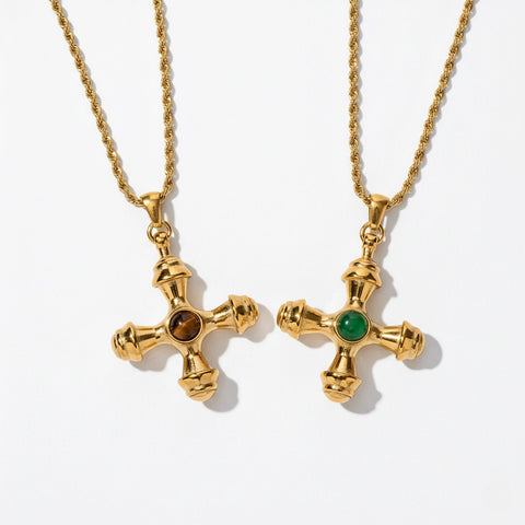 A detailed studio shot of The Jupiter Necklace by Luminova, showcasing both the Tiger Eye and Green Agate gemstone options in the vintage-style gold cross pendant.