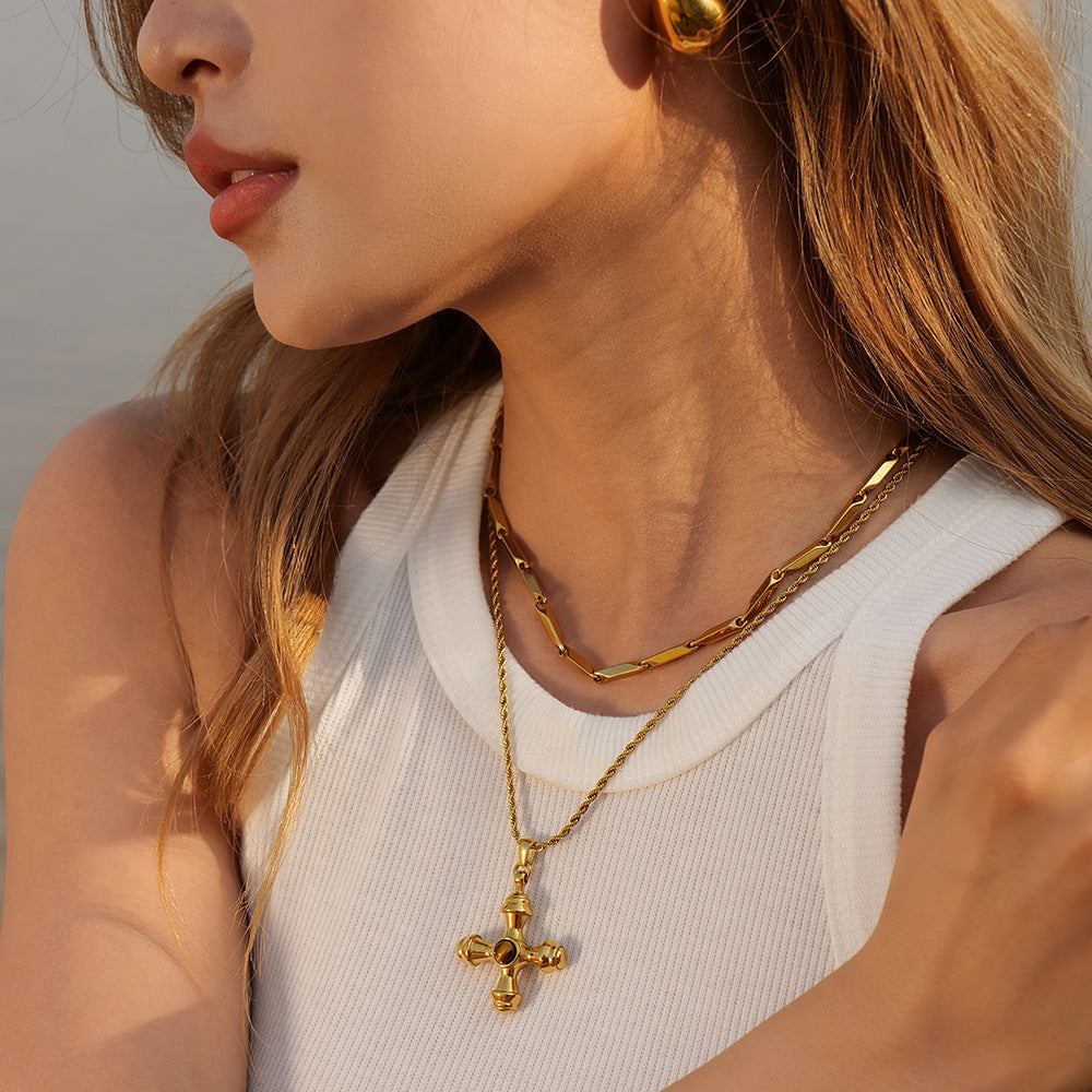 An elegant model wearing The Jupiter cross necklace, demonstrating its perfect length and how it serves as a powerful statement of faith and style.