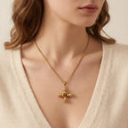 Close up of woman wearing gold Jupiter necklace with vintage cross pendant and amber stone.