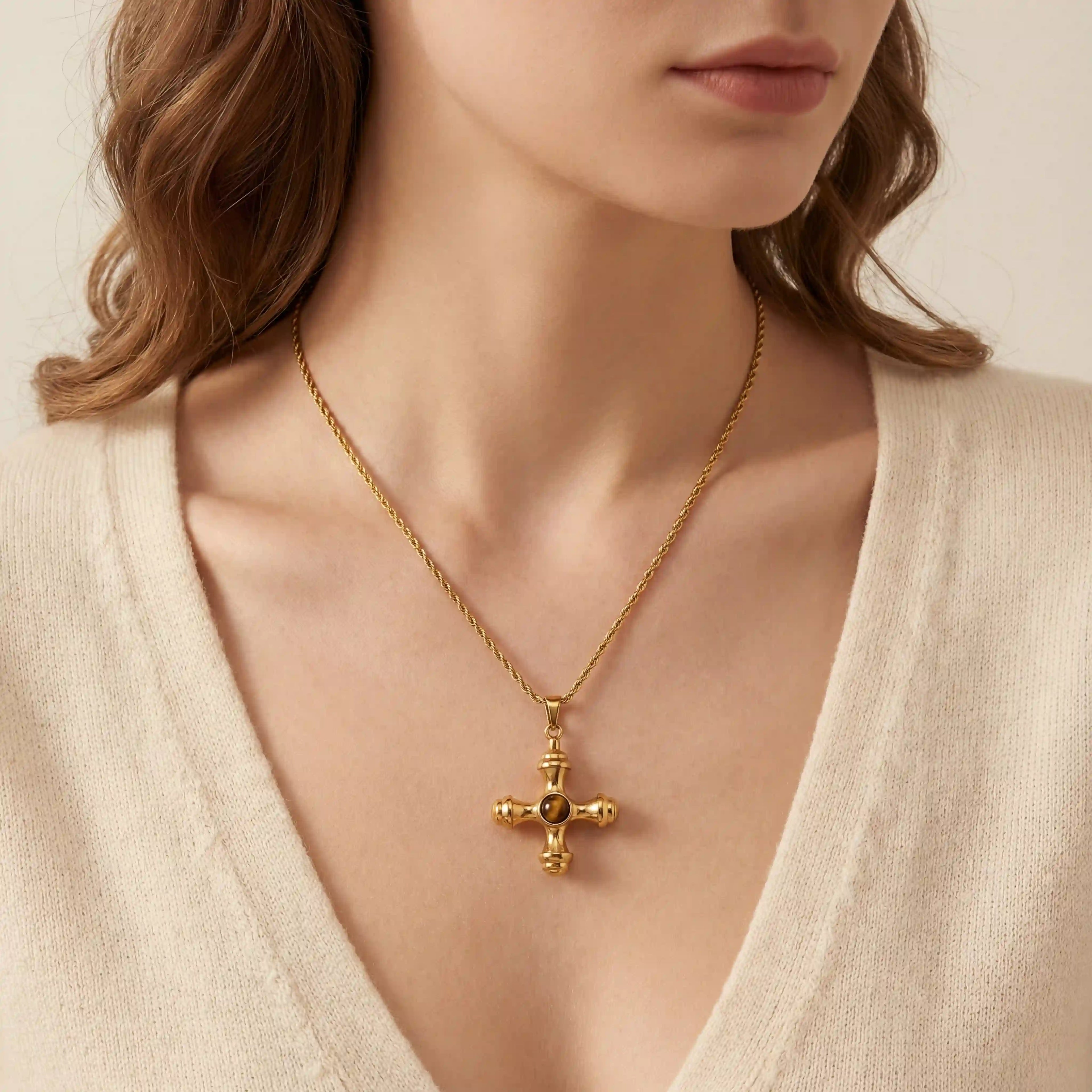 Close up of woman wearing gold Jupiter necklace with vintage cross pendant and amber stone.