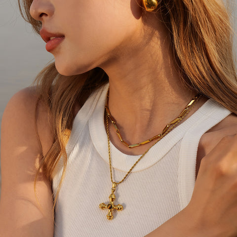 An elegant model wearing The Jupiter cross necklace, demonstrating its perfect length and how it serves as a powerful statement of faith and style.