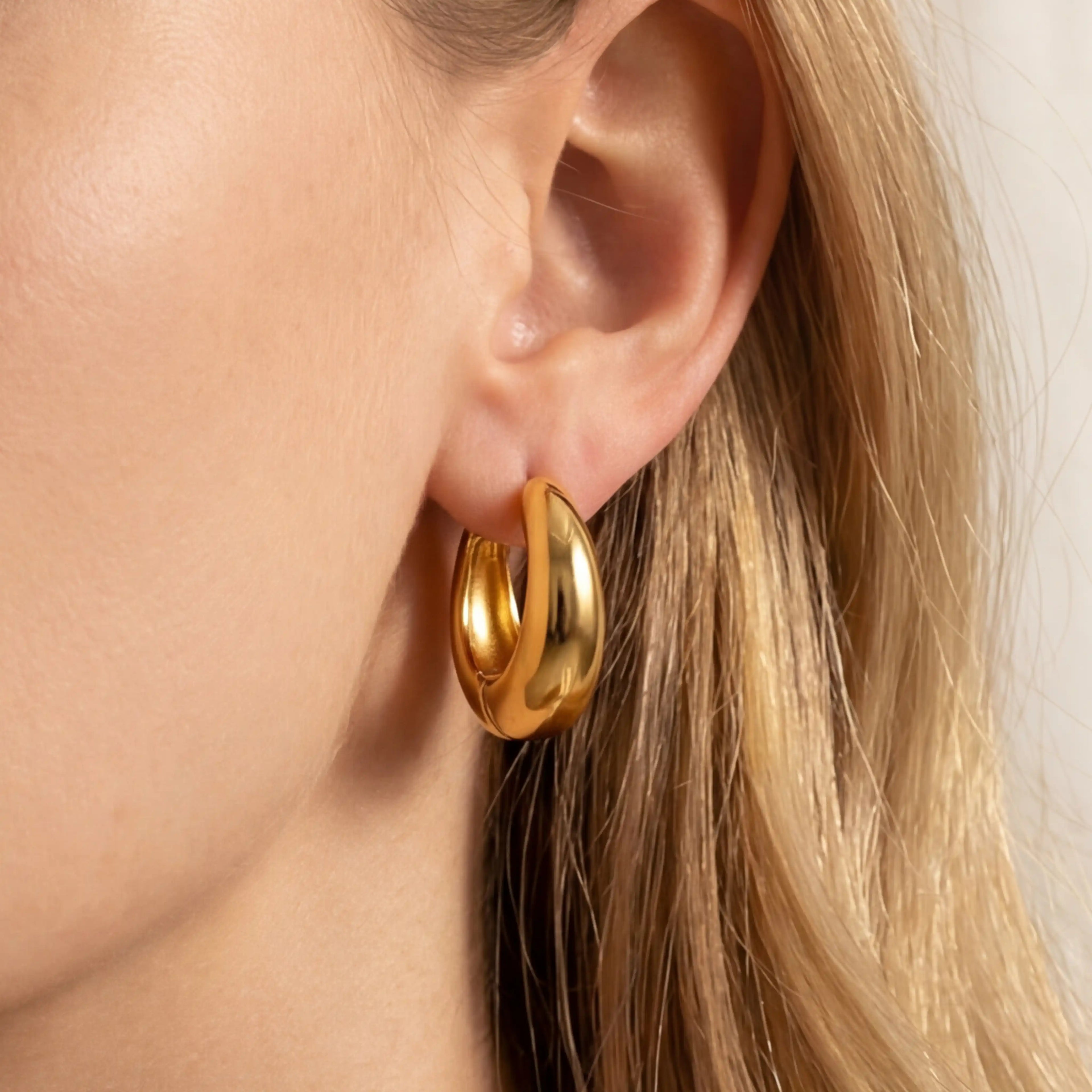 Gold teardrop hoop earrings on ear, lightweight chunky gold hoops for women, hypoallergenic stainless steel waterproof jewelry.