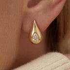 Close up of woman wearing Lucina gold teardrop stud earrings with embedded pear cut crystal.