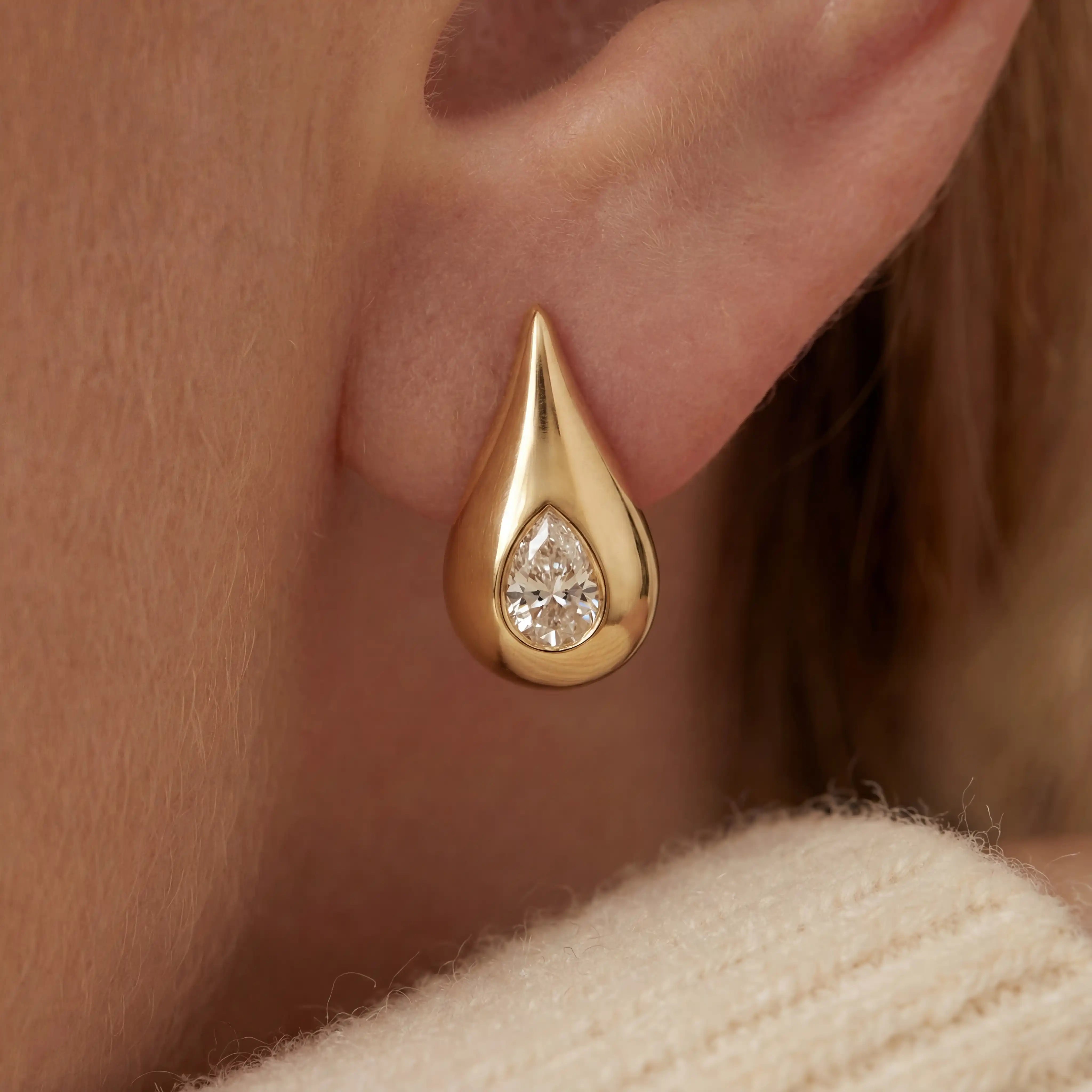 Close up of woman wearing Lucina gold teardrop stud earrings with embedded pear cut crystal. Main image