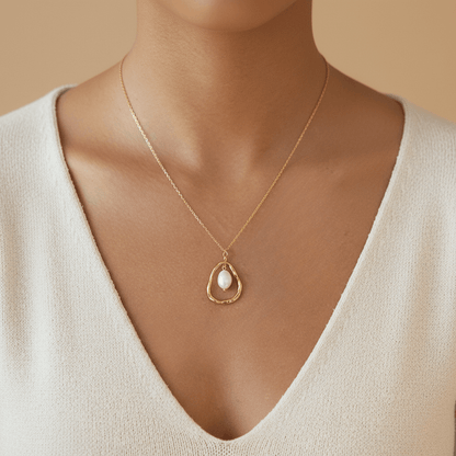 A model wearing a beige cashmere sweater with The Luna Pearl necklace resting on her collarbone, creating a look of quiet luxury and everyday elegance.