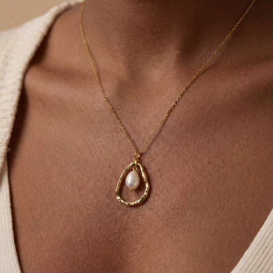 Close up of woman wearing gold Luna necklace with organic open circle and baroque pearl pendant.