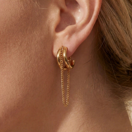Close up of woman wearing gold luxe layered chain hoop earrings with dangling chain detail.