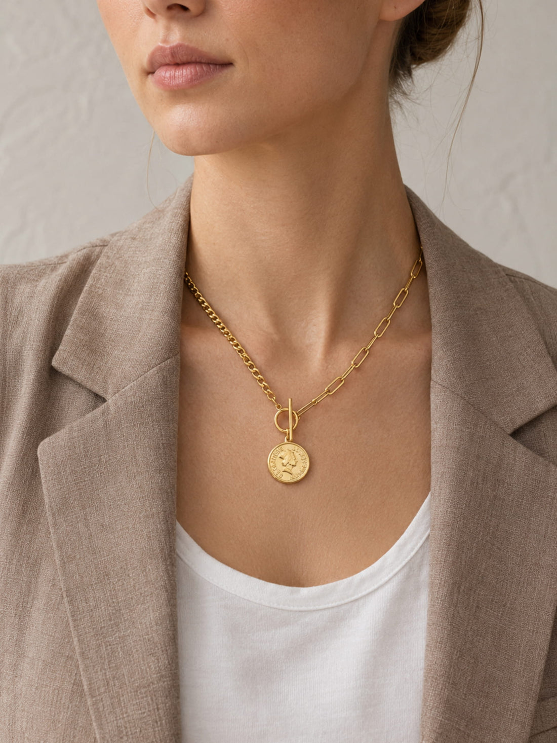 Gold coin pendant toggle necklace worn by model with white tank top