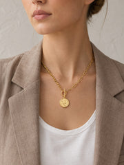 Gold coin pendant toggle necklace worn by model with white tank top