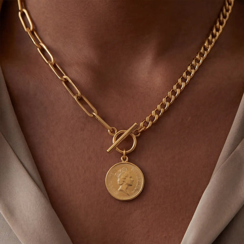 Close up of mixed chain coin necklace with front toggle clasp on model wearing beige top.