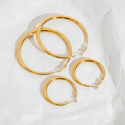 Size comparison of Mneme gold hoops small medium and large flat lay.