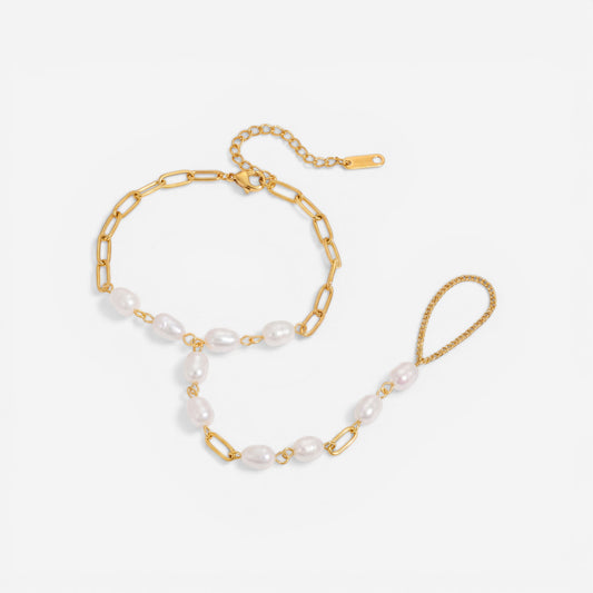 A detailed studio shot of The Nereid Hand Chain by Luminova, showing the delicate bracelet-ring design with freshwater pearls and gold paperclip links.
