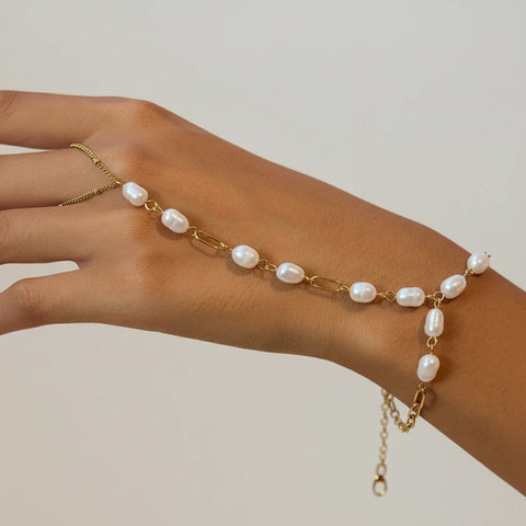A beautiful close-up of The Nereid Hand Chain draping elegantly across a model's hand, showcasing the cascade of freshwater pearls.