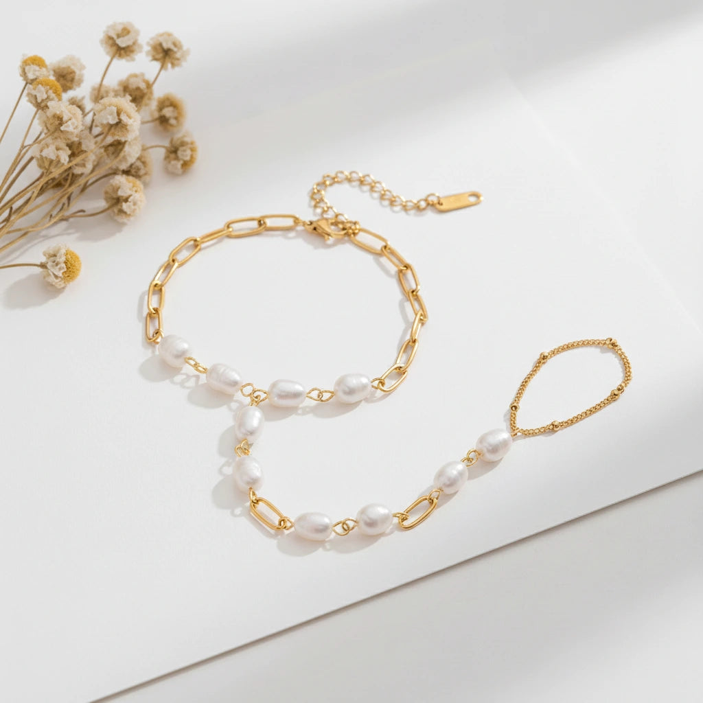 A detailed studio shot of The Nereid Hand Chain by Luminova, showing the delicate bracelet-ring design with freshwater pearls and gold paperclip links.