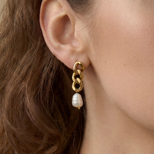 Close up of woman wearing gold chain link earrings with baroque pearl drop Odette style.