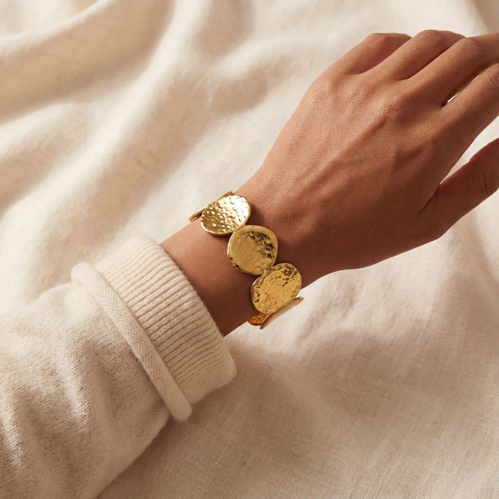 Woman wearing hammered gold disc bangle with cozy beige sweater fall fashion.