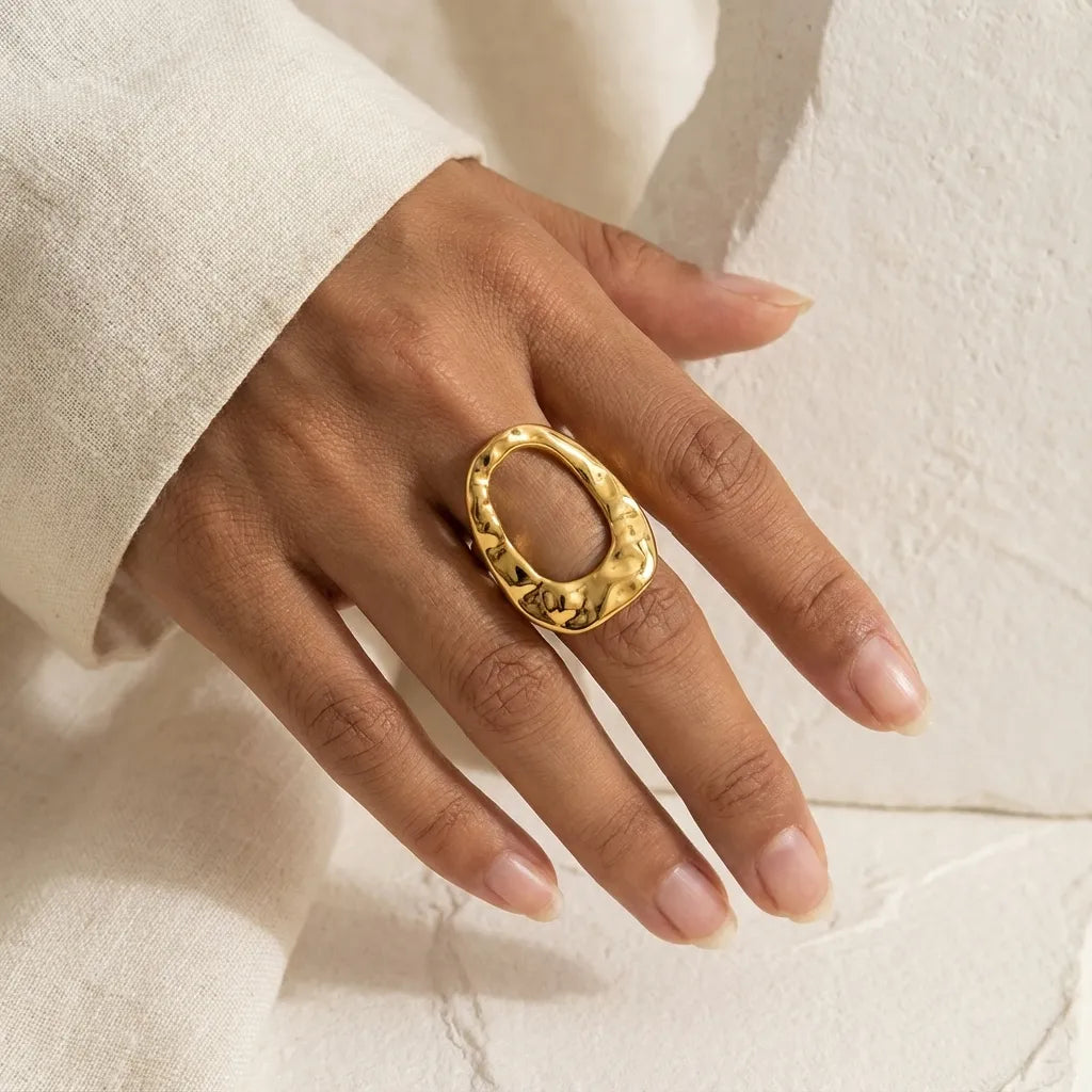 Woman wearing bold organic hammered gold ring on index finger cozy style.
