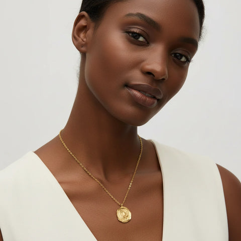 Model wearing matte gold zodiac pendant necklace with white top everyday jewelry style.