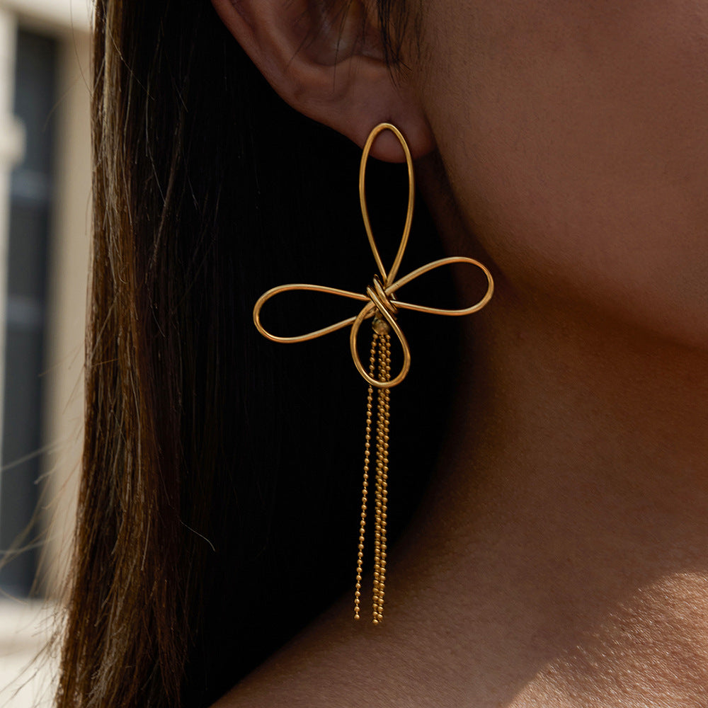 A model's ear adorned with The Psyche Earring, showing the graceful movement of the golden tassel and the intricate, minimalist wire-work of the butterfly.