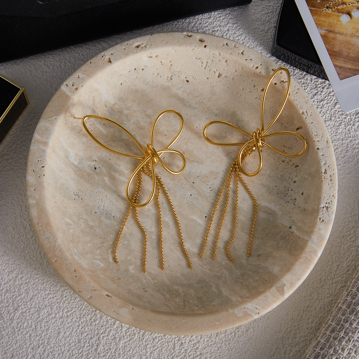 An artistic flat lay of The Psyche Earrings resting on a rustic ceramic plate, emphasizing their delicate, handcrafted, and modern aesthetic.