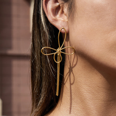 An intimate close-up of The Psyche Earring on a model, focusing on the texture of the gold tassel and the delicate, airy feel of the butterfly design.